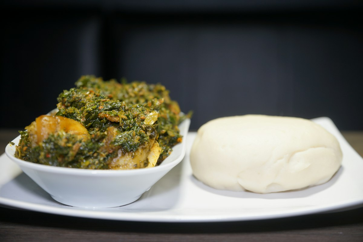Efo riro vegetable soup beside a mound of pounded yam